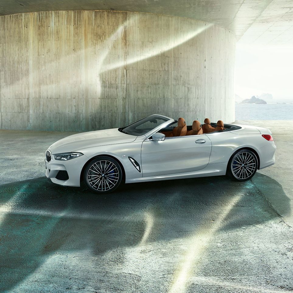 BMW M850i xDrive בצבע Mineral White מטאלי, מבט צד עם גג רך פתוח. BMW M850i xDrive בצבע Mineral White מטאלי, מבט צד עם גג רך פתוח.