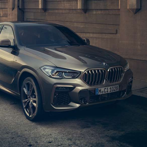 BMW X6 M50i. BMW X6 M50i, מבט 3/4 קדמי בעמידה לפני תמונת נוף עירוני.