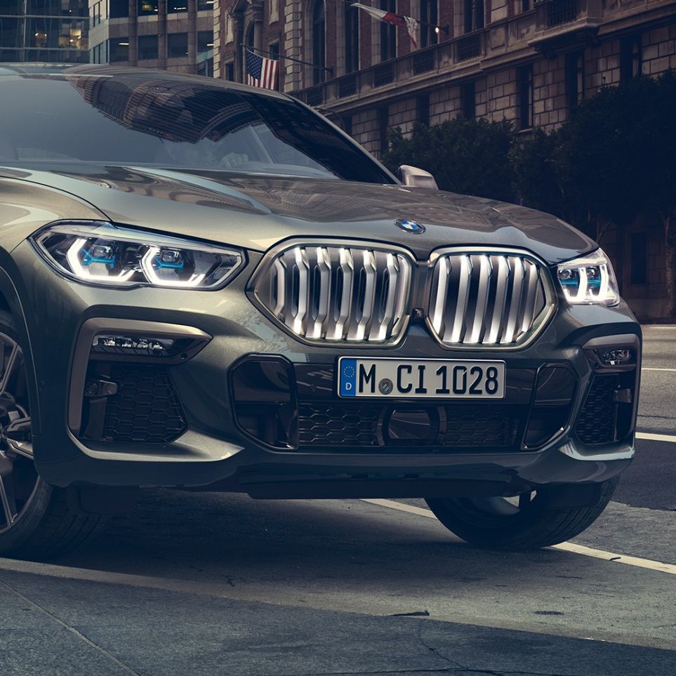 BMW X6 M50i עומד. BMW X6 M50i, מבט 3/4 קדמי בעמידה לפני תמונת נוף עירוני.
