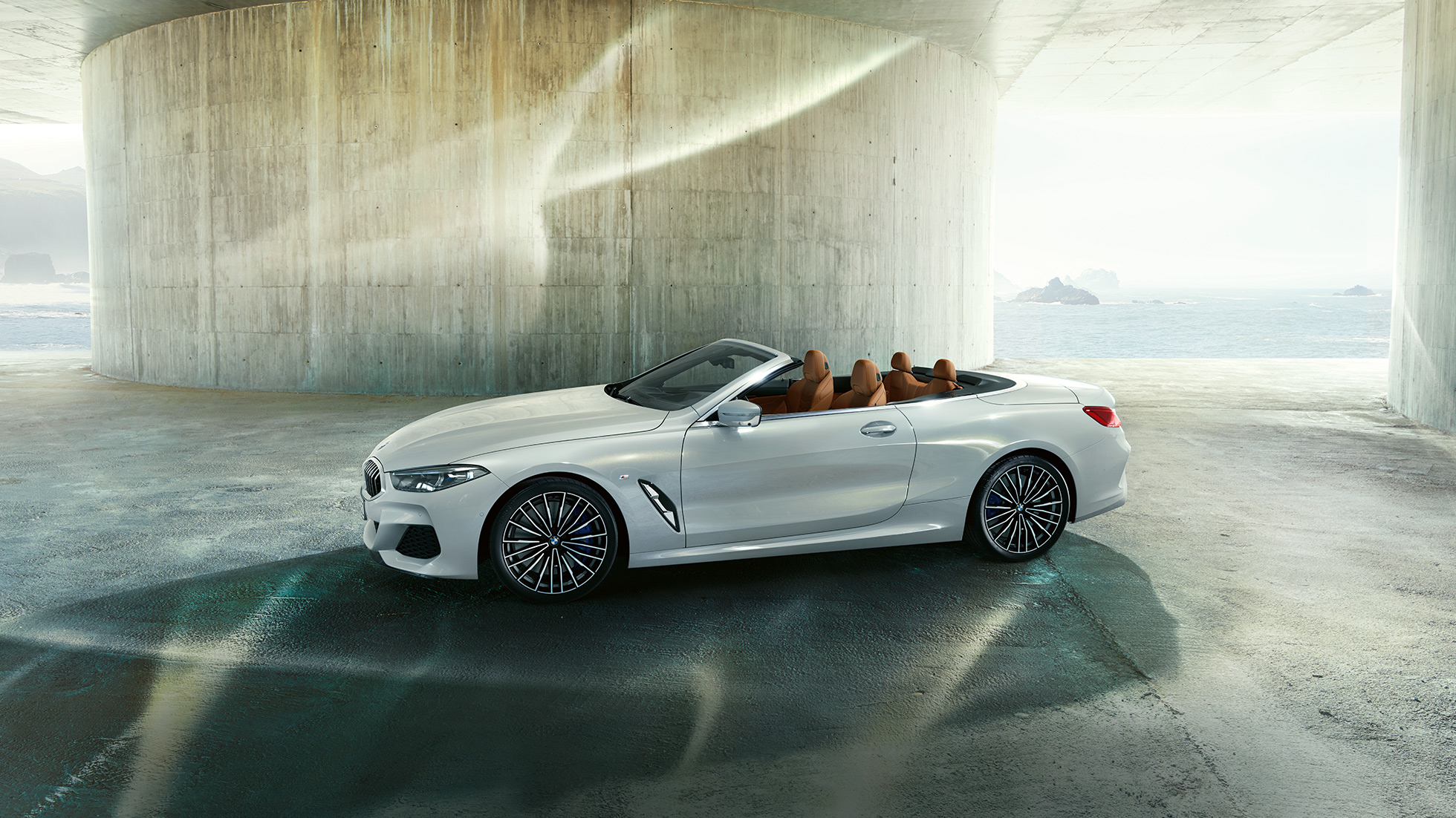 BMW M850i xDrive בצבע Mineral White מטאלי, מבט צד עם גג רך פתוח. BMW M850i xDrive בצבע Mineral White מטאלי, מבט צד עם גג רך פתוח.