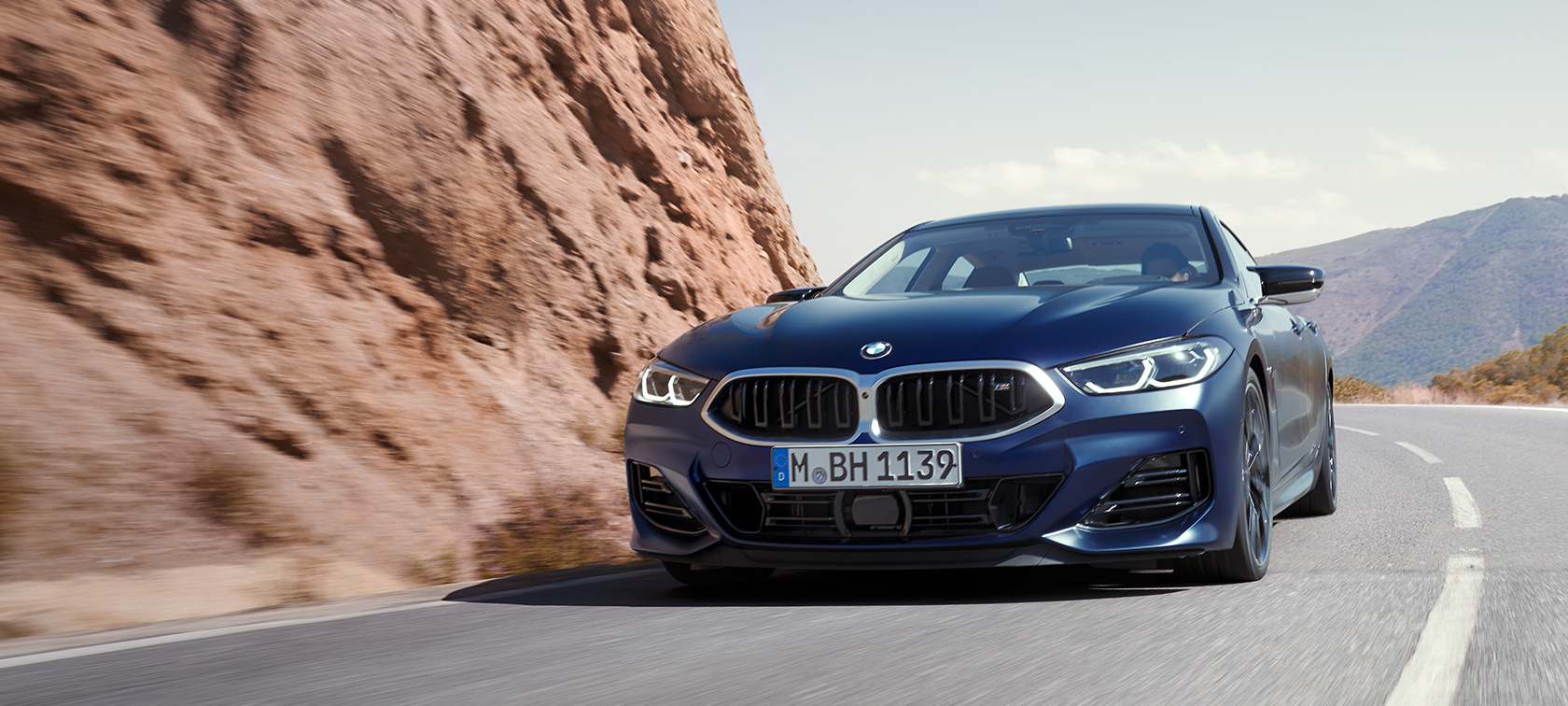 BMW סדרה 8 גראן קופה LCI מתיחת פנים מבט קדמי נהיגה בכביש הררי BMW 8 Series Gran Coupé G16 LCI Facelift 2022 BMW Individual Frozen Tanzanite Blue metallic three-quarter front view driving on a mountain road