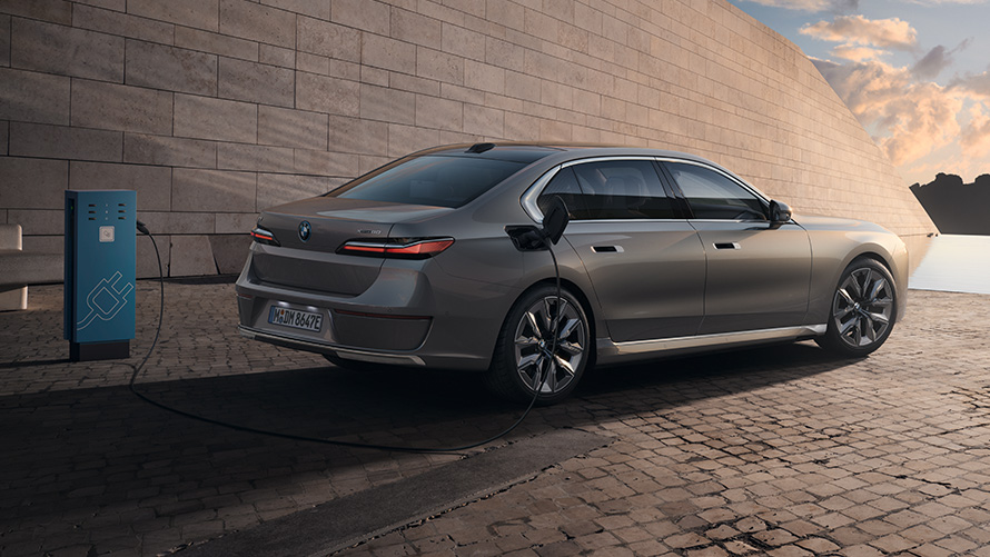 BMW i7 Sedan G70 – מבט צדדי מאחור BMW i7 Sedan G70 BMW Individual אפור Oxid מטאלי מבט צדדי בתחנת טעינה