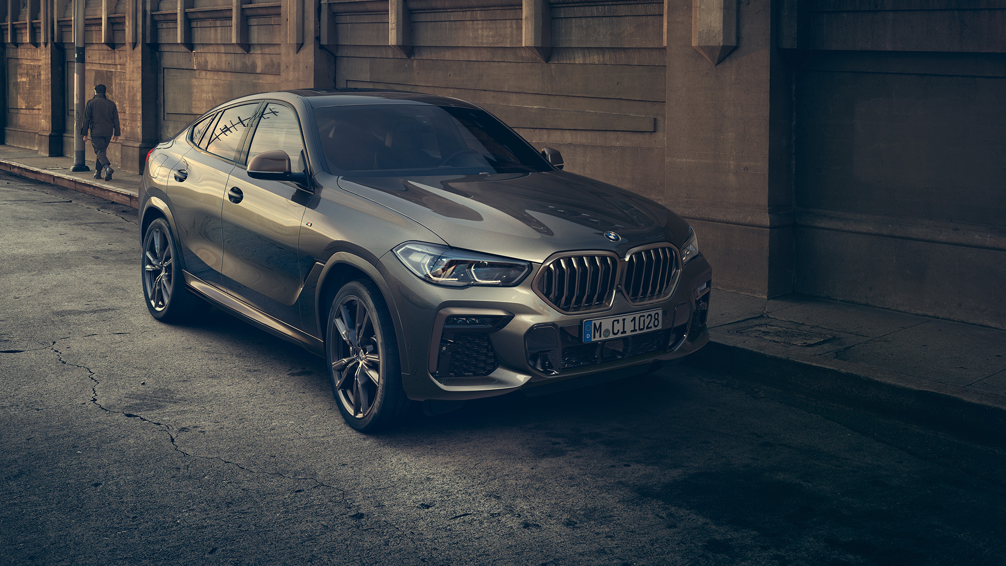 BMW X6 M50i. BMW X6 M50i, מבט 3/4 קדמי בעמידה לפני תמונת נוף עירוני.