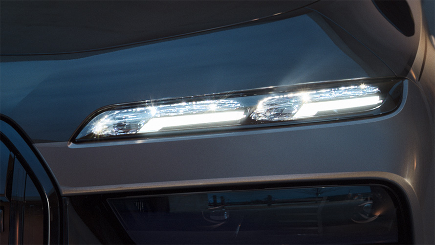 פנסים ראשיים בגימור קריסטל BMW Iconic Glow‏ BMW M760e xDrive שני גווני שחור מטאלי BMW Individual Black Sapphire אפור BMW Individual Dravite Grey מטאלי צילום תקריב עם אורות דולקים