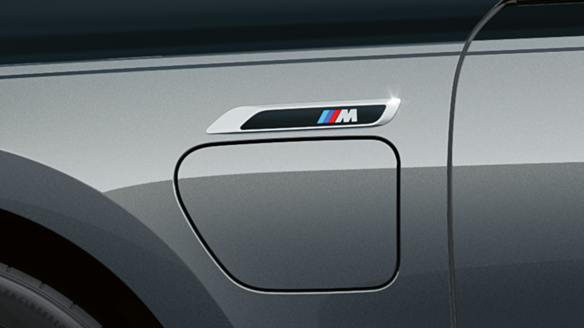 סמל M BMW M760e xDrive סמל M BMW M760e xDrive חבילת M Performance שני גווני שחור מטאלי BMW Individual Black Sapphire אפור BMW Individual Dravite Grey מטאלי צילום תקריב מבט צדדי