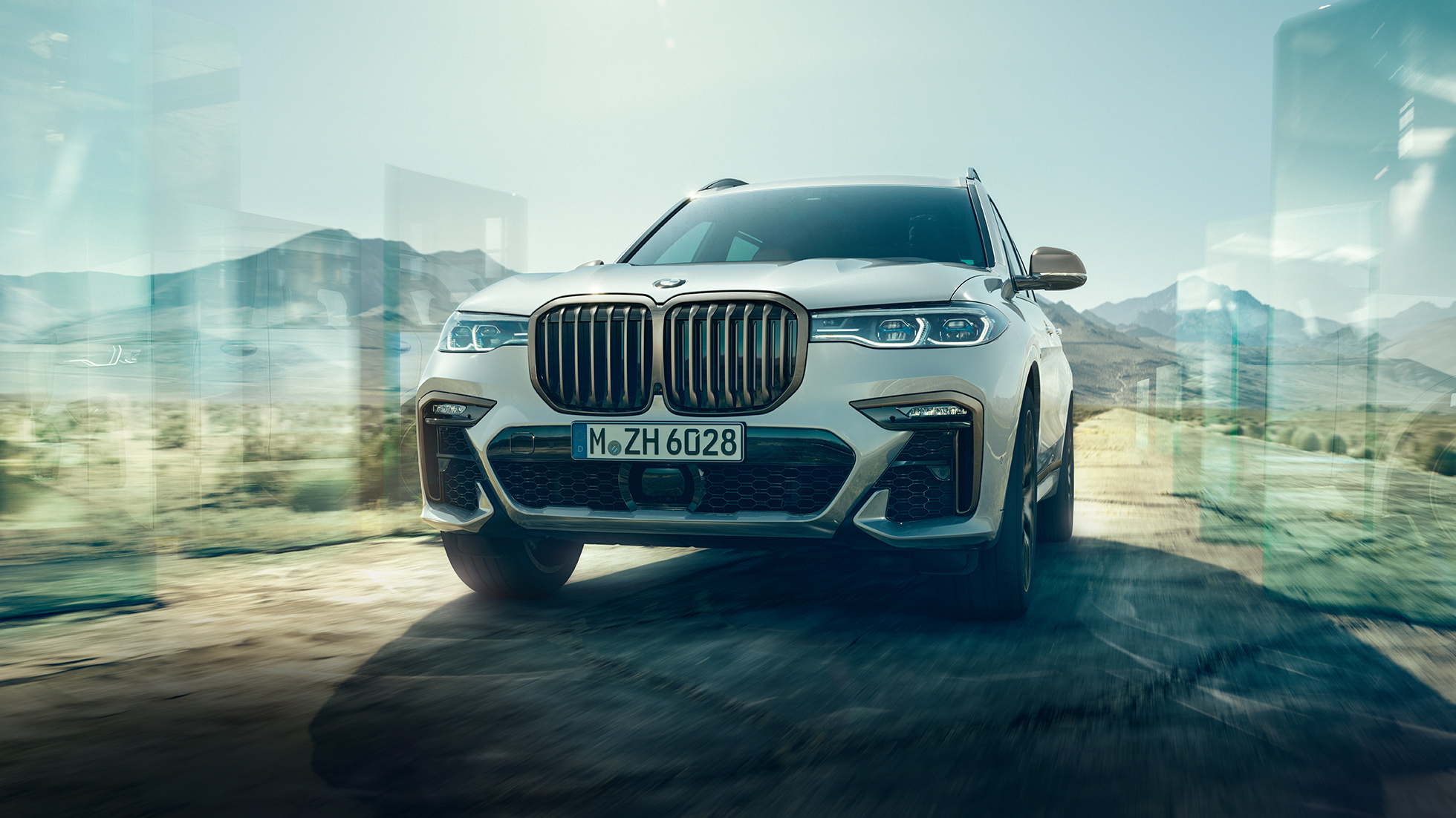 BMW X7 M50d, תצלום מזווית נמוכה BMW X7 M50d: תצלום במבט אלכסוני מזווית נמוכה על BMW X7 לבן בנסיעה