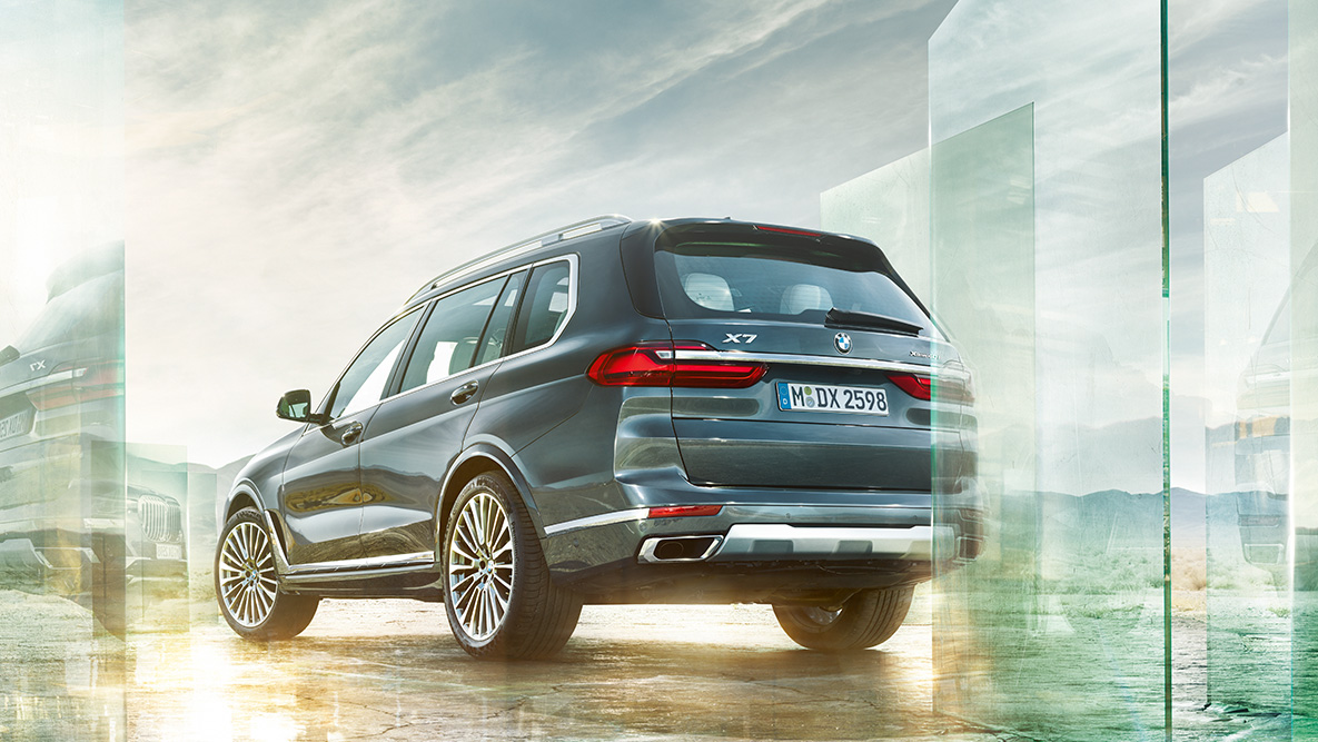 נוחות ויכולות דינאמיות ב-BMW X7 BMW X7 במבט חלק אחורי-צד על רקע נוף מופשט